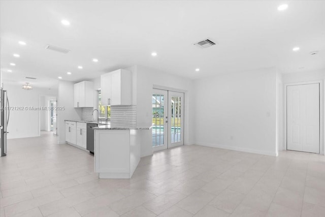 kitchen featuring light stone countertops, white cabinets, stainless steel appliances, french doors, and backsplash