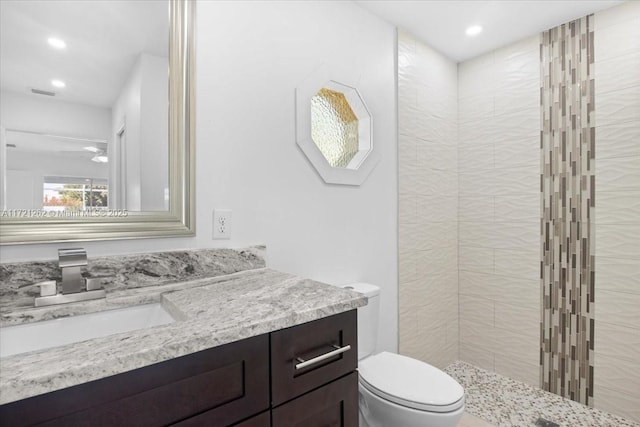 bathroom with vanity, toilet, and a tile shower