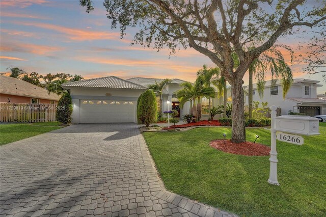 mediterranean / spanish-style home featuring a yard and a garage