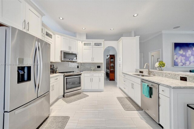 kitchen featuring sink, stainless steel appliances, light stone countertops, decorative backsplash, and white cabinets