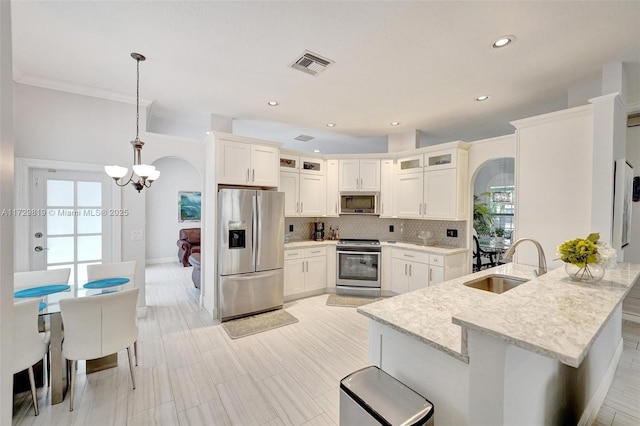 kitchen featuring pendant lighting, sink, appliances with stainless steel finishes, white cabinetry, and backsplash