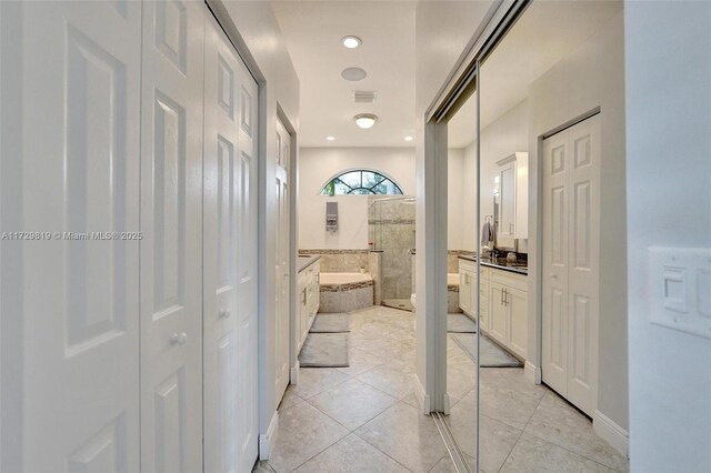 bathroom featuring vanity, tile patterned floors, and tiled bath