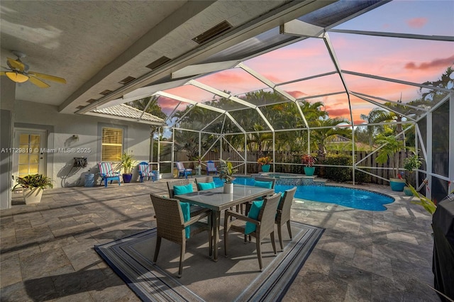 pool at dusk with ceiling fan, a lanai, and a patio area