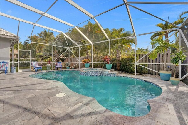 view of pool with an in ground hot tub, a patio, and glass enclosure