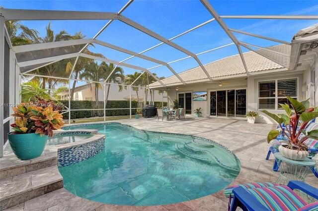 view of pool with an in ground hot tub, glass enclosure, and a patio area