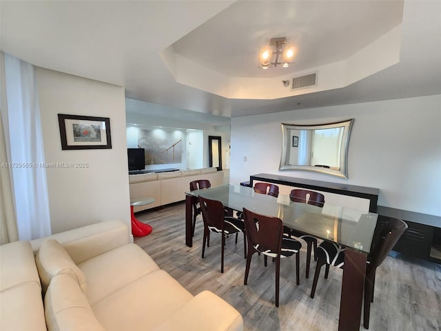 dining room with hardwood / wood-style floors and a raised ceiling