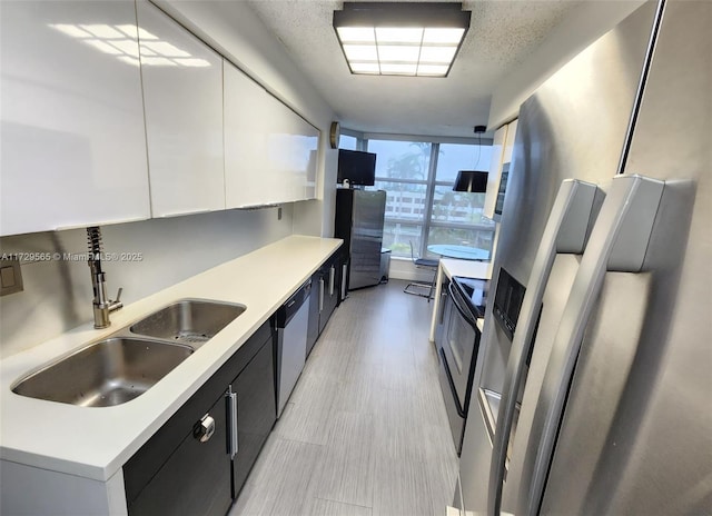 kitchen with sink, white cabinets, a textured ceiling, and stainless steel appliances