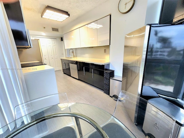 kitchen featuring sink, a textured ceiling, white cabinets, and stainless steel appliances