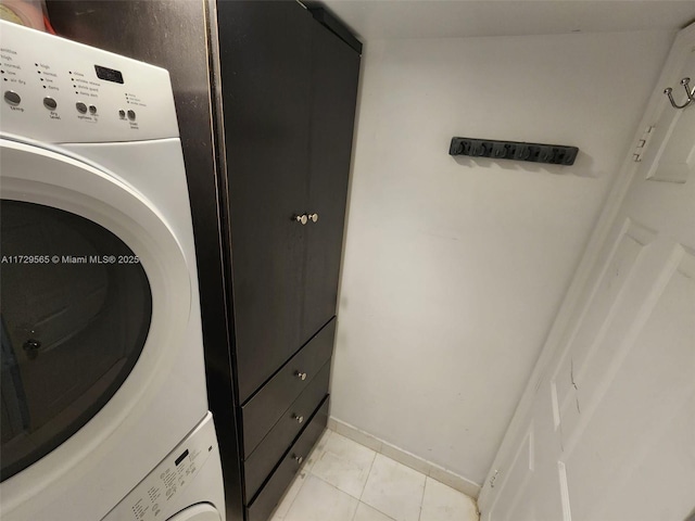 laundry area featuring light tile patterned floors and stacked washer / dryer