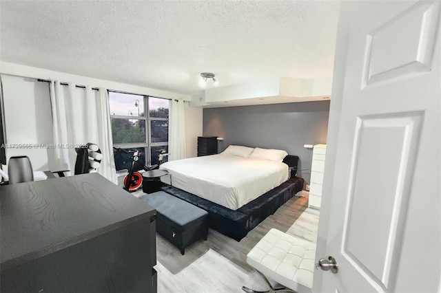 bedroom featuring light hardwood / wood-style floors and a textured ceiling