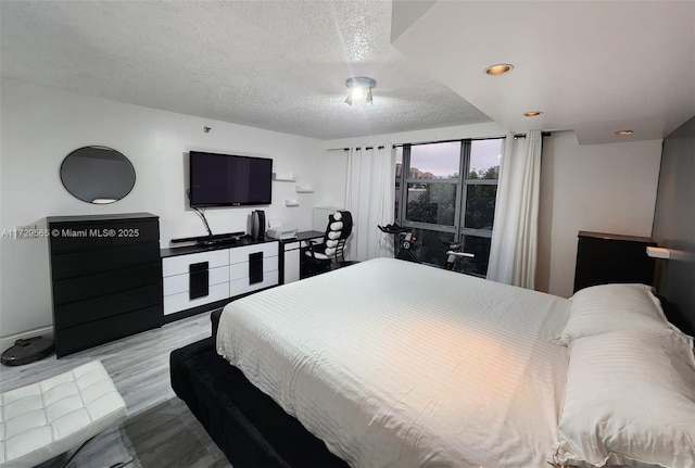 bedroom featuring light hardwood / wood-style floors and a textured ceiling