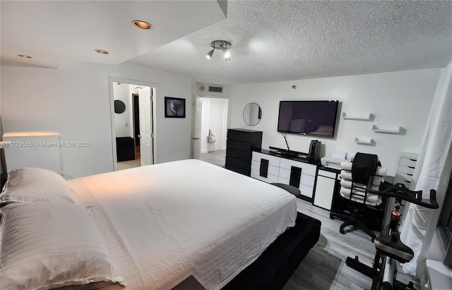 bedroom featuring a textured ceiling and light hardwood / wood-style flooring