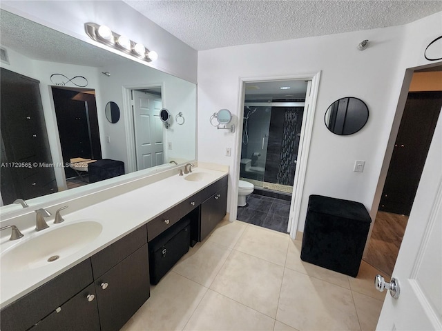 bathroom featuring a textured ceiling, tile patterned floors, a shower with door, vanity, and toilet