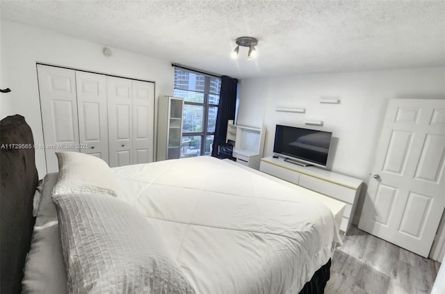 bedroom with floor to ceiling windows, a textured ceiling, a closet, and light hardwood / wood-style flooring