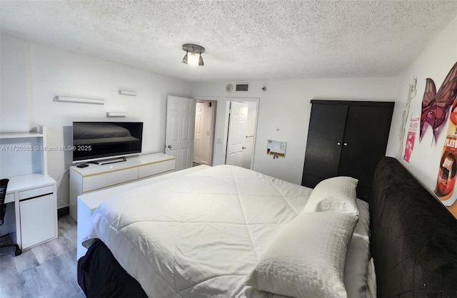 bedroom featuring a textured ceiling and light hardwood / wood-style flooring