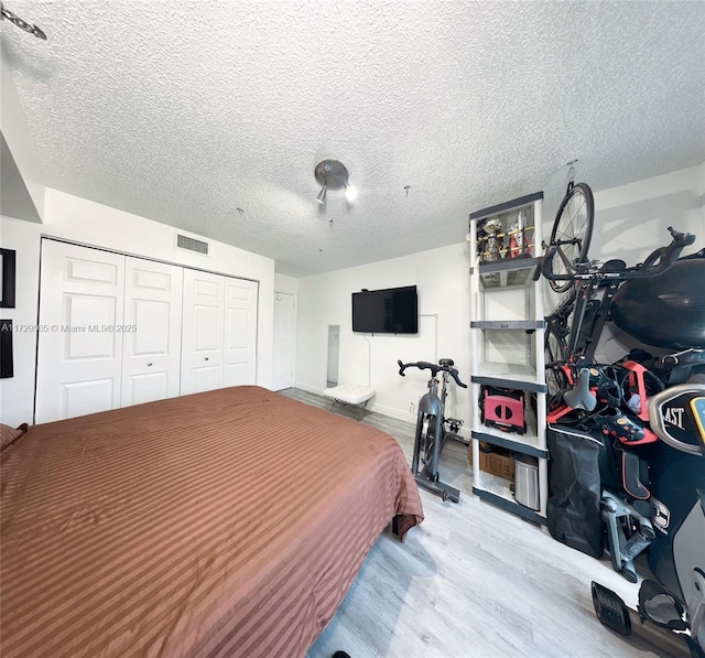 bedroom with a closet, hardwood / wood-style floors, and a textured ceiling