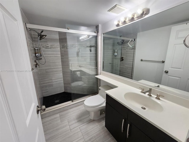 bathroom with toilet, a shower with shower door, and vanity