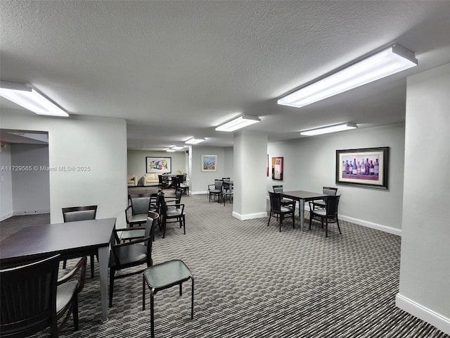 dining space featuring a textured ceiling and dark colored carpet