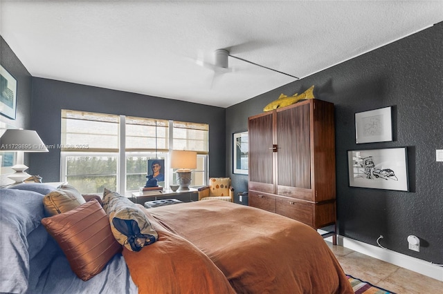 bedroom featuring ceiling fan, light tile patterned floors, and a textured ceiling