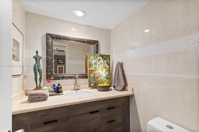 bathroom with tile walls, toilet, and vanity