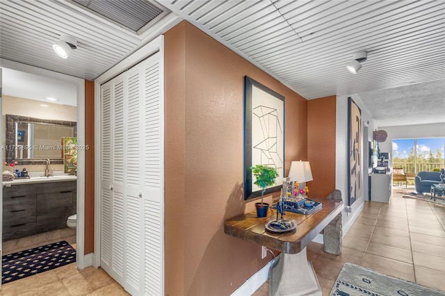 corridor featuring sink and light tile patterned floors