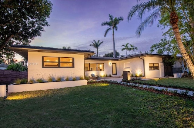 view of front of home with central air condition unit and a lawn