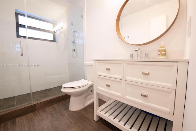 bathroom featuring hardwood / wood-style flooring, toilet, a shower with shower door, and vanity