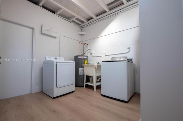 washroom featuring sink, light hardwood / wood-style flooring, water heater, and washing machine and clothes dryer