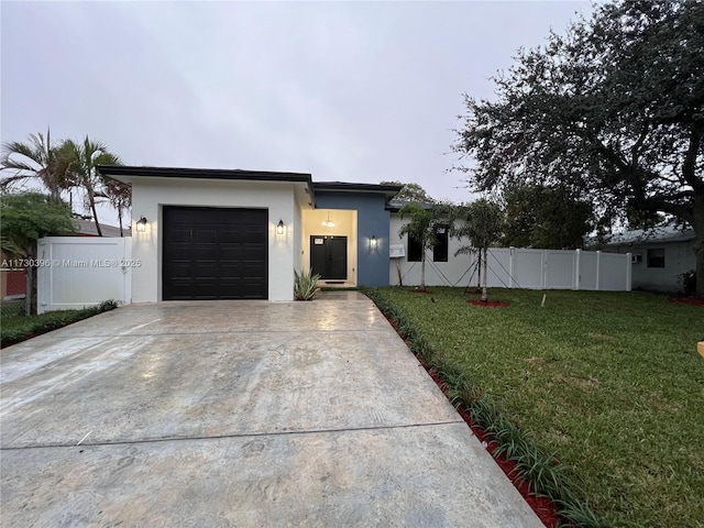 contemporary home with an attached garage, a front yard, fence, and stucco siding
