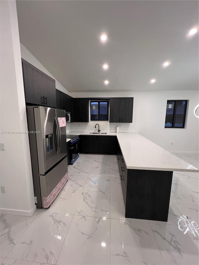 kitchen with a peninsula, appliances with stainless steel finishes, marble finish floor, and a sink