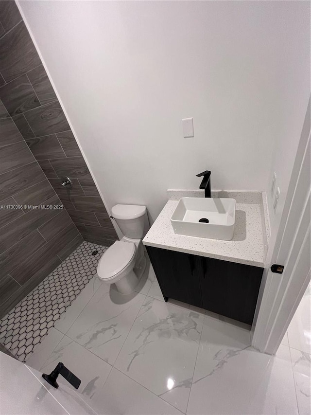 bathroom featuring vanity, toilet, and tiled shower