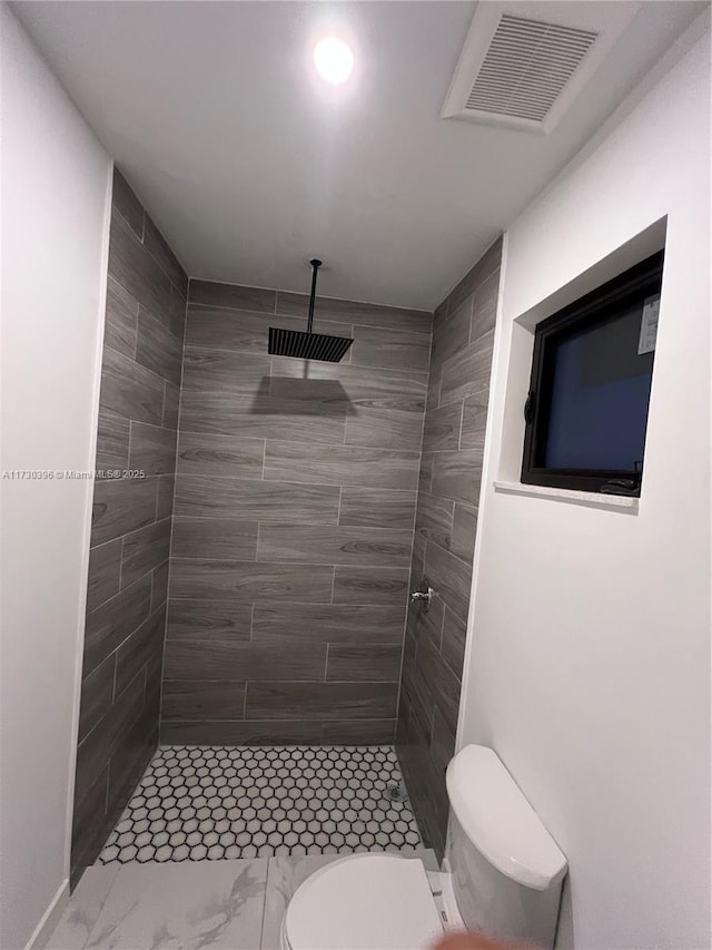 bathroom with tiled shower and toilet