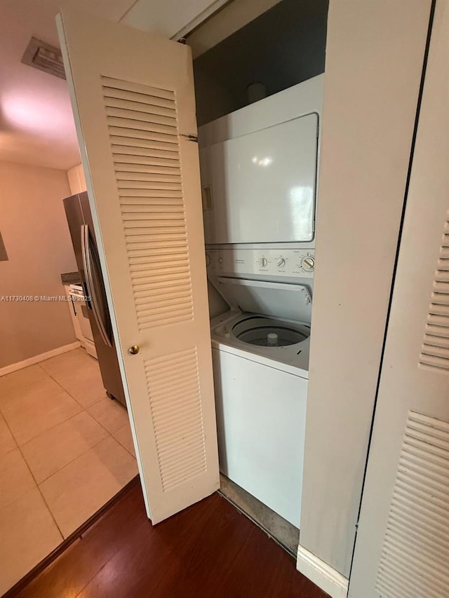 laundry area with wood-type flooring and stacked washer / drying machine