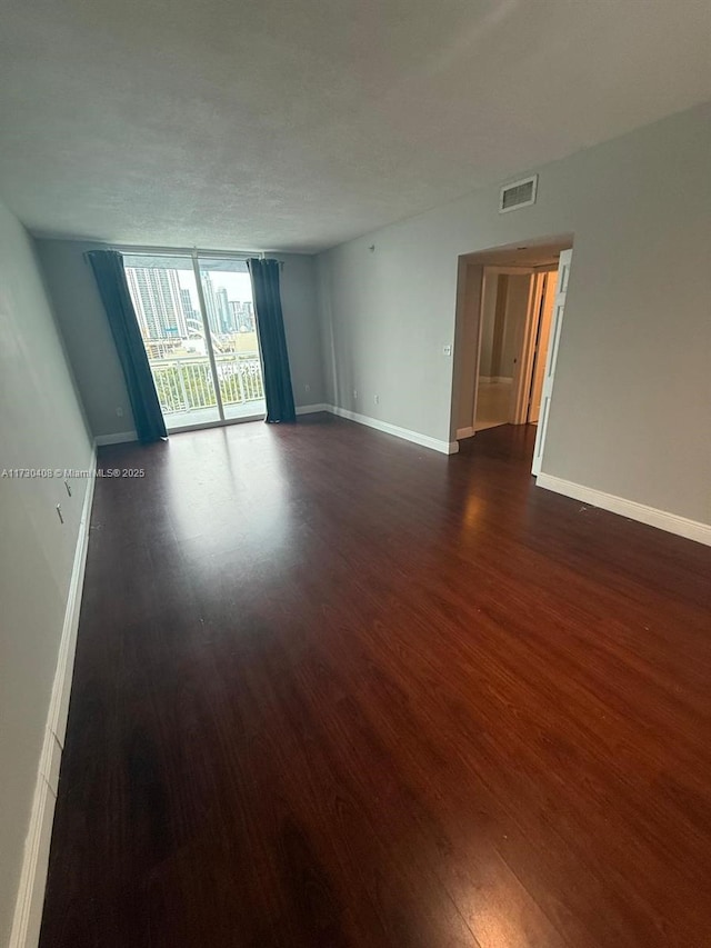 spare room with a textured ceiling, dark hardwood / wood-style floors, and expansive windows