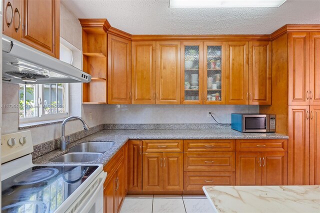 kitchen with light tile patterned floors, black fridge, and a textured ceiling