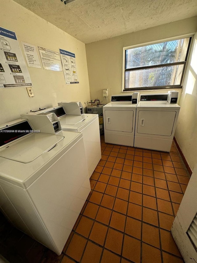 clothes washing area with dark tile patterned floors, washer and dryer, and a textured ceiling