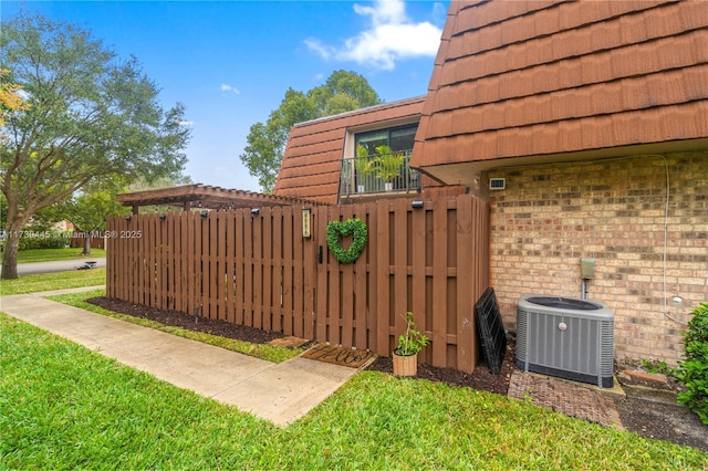 view of gate with fence, cooling unit, and a yard