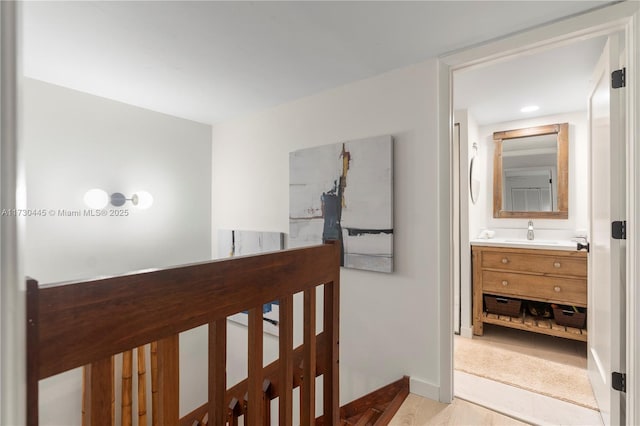 hall with a sink, an upstairs landing, and baseboards