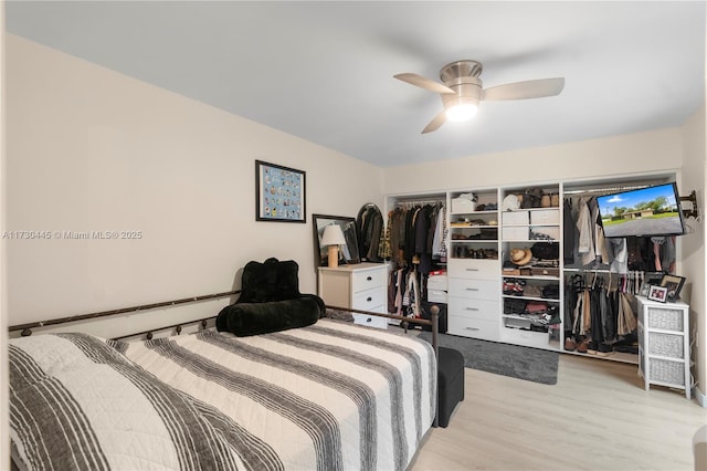 bedroom with light wood-type flooring, ceiling fan, a baseboard heating unit, and a closet