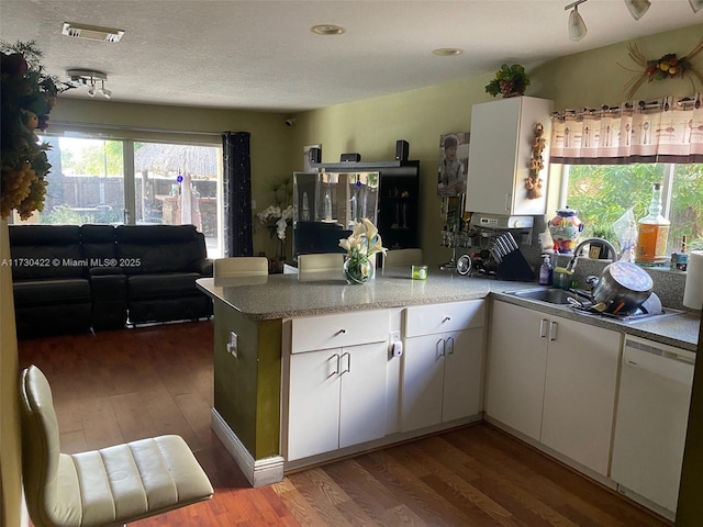 kitchen featuring dishwasher, white cabinetry, dark hardwood / wood-style flooring, sink, and kitchen peninsula