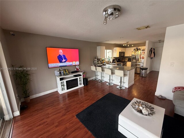 kitchen featuring white cabinets, dark hardwood / wood-style flooring, stainless steel appliances, kitchen peninsula, and a breakfast bar area