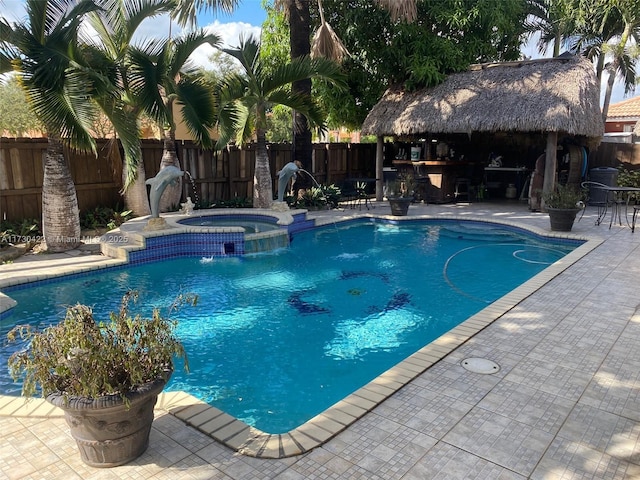 view of pool featuring pool water feature, an in ground hot tub, a patio, and an outdoor bar