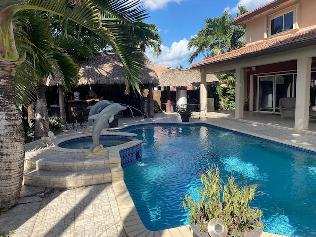 view of pool with an in ground hot tub, a patio area, and pool water feature