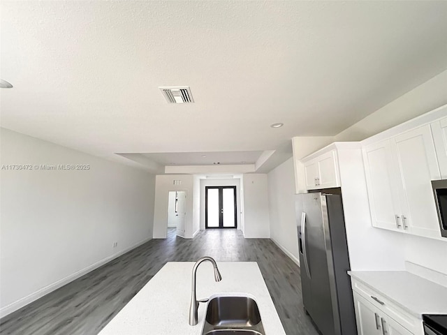 kitchen with appliances with stainless steel finishes, sink, white cabinets, a tray ceiling, and dark hardwood / wood-style floors