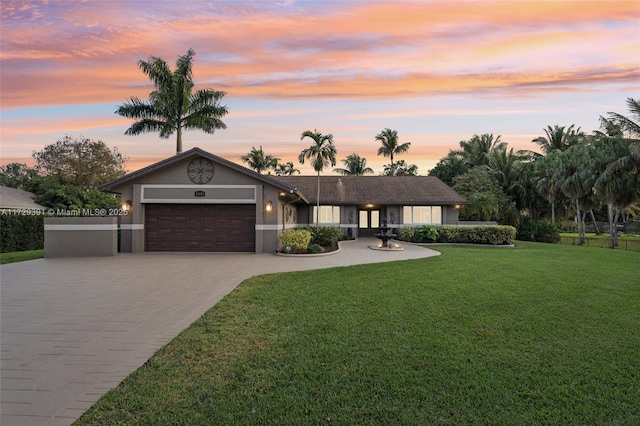 ranch-style house with a garage and a yard