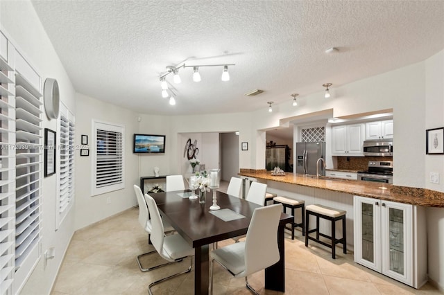 tiled dining room with sink and a textured ceiling