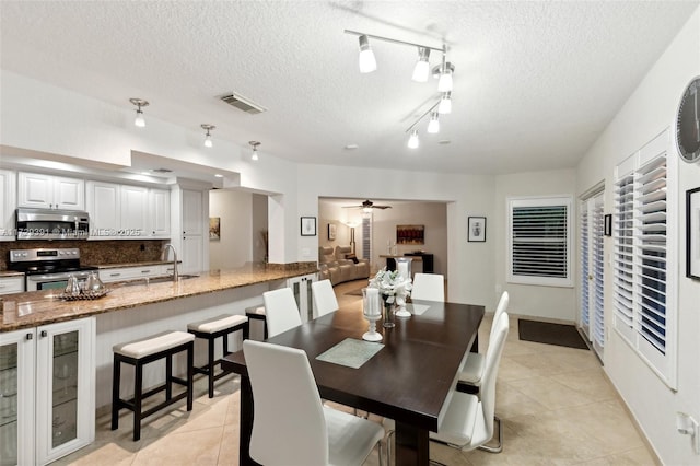 tiled dining room featuring ceiling fan, sink, and a textured ceiling