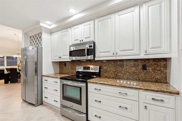 kitchen featuring white cabinetry, dark stone counters, backsplash, stainless steel appliances, and light tile patterned flooring