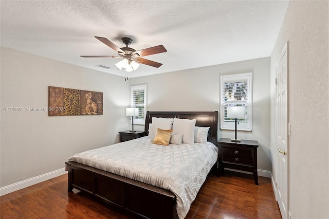 bedroom featuring multiple windows, a textured ceiling, ceiling fan, and dark hardwood / wood-style flooring