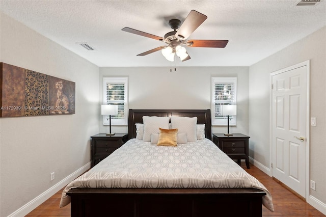 bedroom featuring hardwood / wood-style floors, a textured ceiling, and ceiling fan